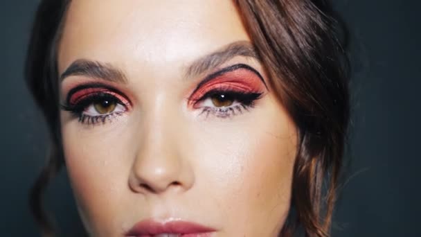 Attraktiv flicka med ljusa makeup på ögonen blinkning. Ung kvinna ansikte — Stockvideo