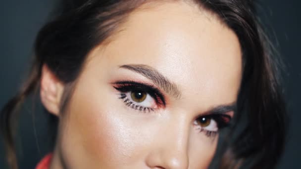 Schöne Brünette mit gemalten Augenbrauen und Wimpern. Make-up im weiblichen Gesicht — Stockvideo