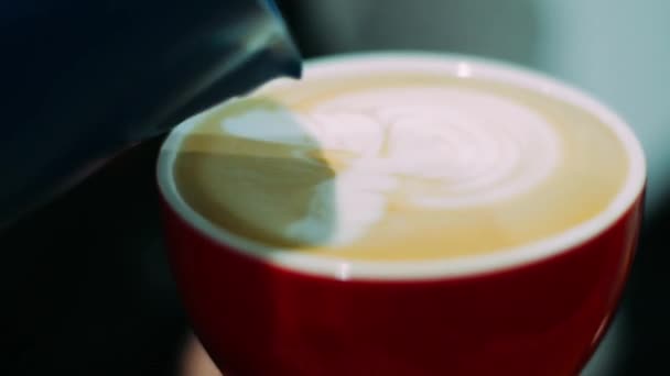 Професійний бариста заливає молоко в чашку кави, роблячи гарний латексний візерунок — стокове відео