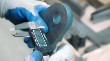 Elektronik kaliper ile demir parçasının iç çapını ölçen işçi