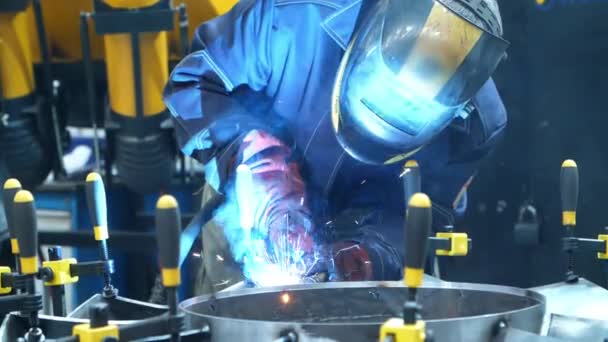 Robotnik w masce wykonujący spawanie metalowych kęseł przymocowany za pomocą uchwytów ręcznych — Wideo stockowe
