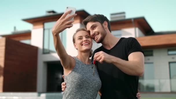 Happy couple making selfie photo with house keys outside residence. — Stock Footage Happy couple making selfie photo with house keys outside residence. Royalty Free Stock Video