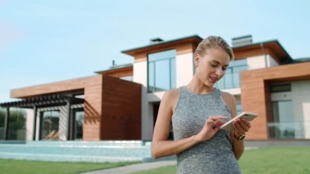 Relaxed woman texting mobile near luxury house. Pretty woman standing near villa — Stock Footage Relaxed woman texting mobile near luxury house. Pretty woman standing near villa Stock Footage