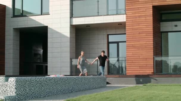 Casal doce correndo perto de casa de luxo. Belo casal correndo grama — Vídeo de Stock