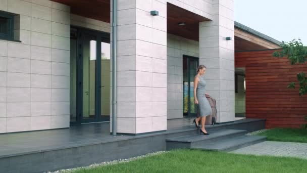 Business woman holding suitcase near luxury house. Business woman leaving hotel. — Stock Video