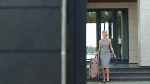 Hermosa mujer saliendo del hotel con equipaje. Chica bonita que va de vacaciones . — Vídeos de Stock