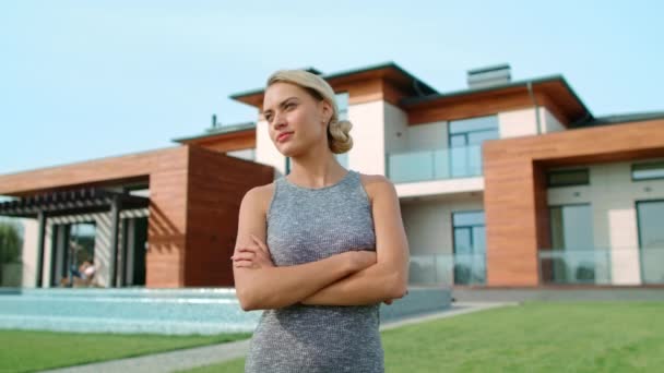 Сконцентрированная женщина, стоящая возле роскошного дома. Женщина отдыхала рядом с виллой — стоковое видео