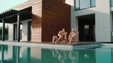 Çift lüks dairelerde güneşleniyor. Kokteyl içen güzel insanlar