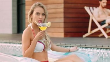 Havuzda kokteyl içen büyüleyici bir kadın. Kokteyli yudumlayan kadının portresi