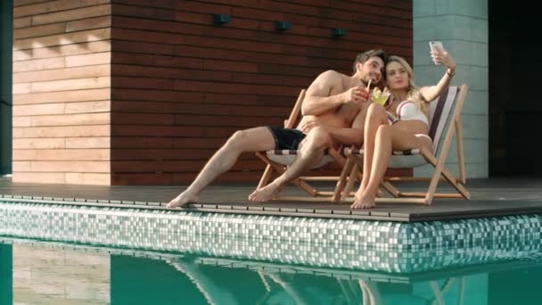 Una pareja besándose tomando selfie cerca de la piscina. Pareja de verano disfrutando de foto selfie . — Vídeo de stock