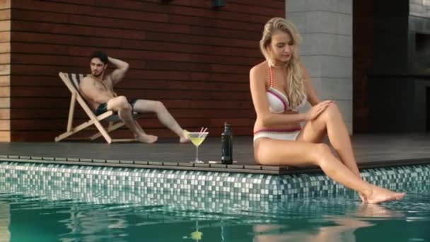 Sexig kvinna som sitter nära poolen. Söt flicka utarmning hud nära pool — Stockvideo