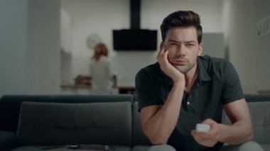 Açık mutfakta kanepede uzaktan kumanda anahtarlama yakışıklı adam.