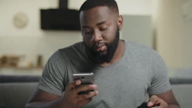 Siyah adam mutfakta telefon tutuyor. Akıllı telefonda Genç Yetişkin manifatura.