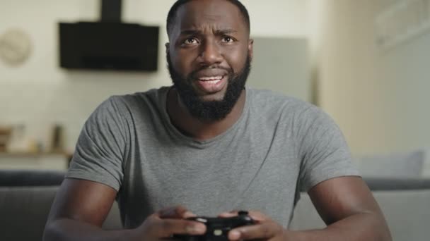 Hombre negro jugando a videojuegos en casa. Retrato del tipo negro sosteniendo la estación de juego — Vídeos de Stock