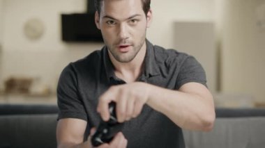 Genç adam video oyunu oynuyor. Açık mutfakta joystick alarak konsantre adam.