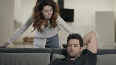 Adam oturma odasında kadına bakıyor. Mutlu çift oturma odasında gülümsüyor