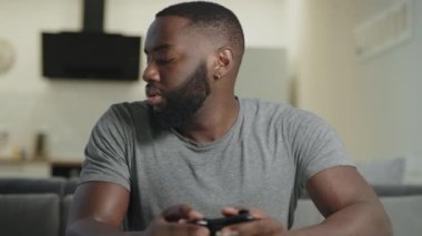 Konsantre adam mutfakta oyun oynuyor. PlayStation tutan sinirli adam