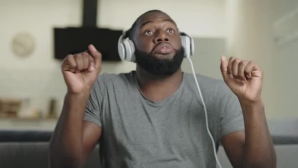 Happy man singing in headphones at kitchen. Male person dancing in headphones. — Stock Video