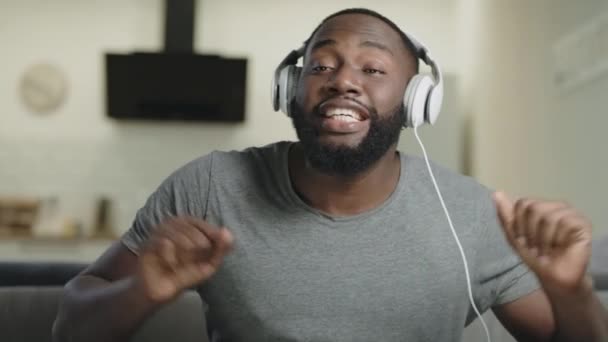 Portrait of male person singing in headphones. Joyful adult listening music. — Stock Video