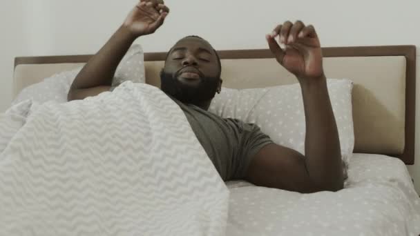 Hombre negro durmiendo en la cama. Joven hombre despertando en el dormitorio lentamente . — Vídeos de Stock