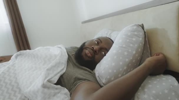 Black man listening noise in morning. Irritated male person waking up in bed. — Stock Video