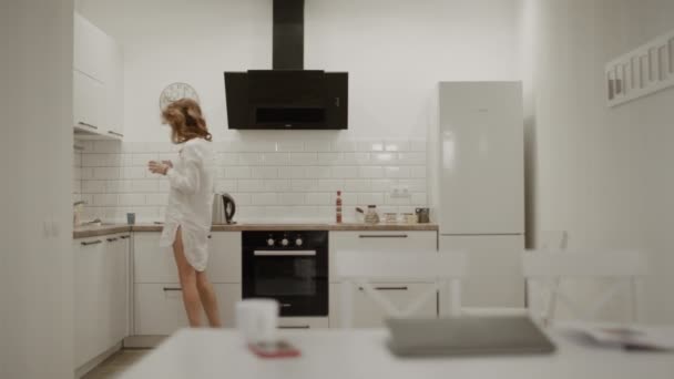 Fröhliche junge Frau, die in der Küche Kaffee kocht. Lächelnde Dame bekommt Nachricht — Stockvideo