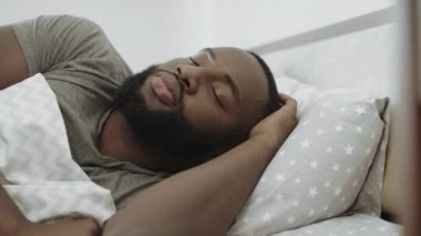 Sabah yatakta uyuyan Afrikalı adam. Mutsuz erkek kişi sabah nefret.