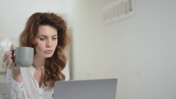 Mujer seria mirando el ordenador portátil en la cocina abierta . — Vídeos de Stock