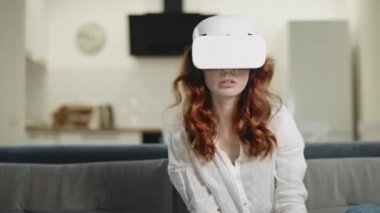VR gözlüklü kanepede oturan ciddi bir kadın. Şok kadın VR bakıyor.