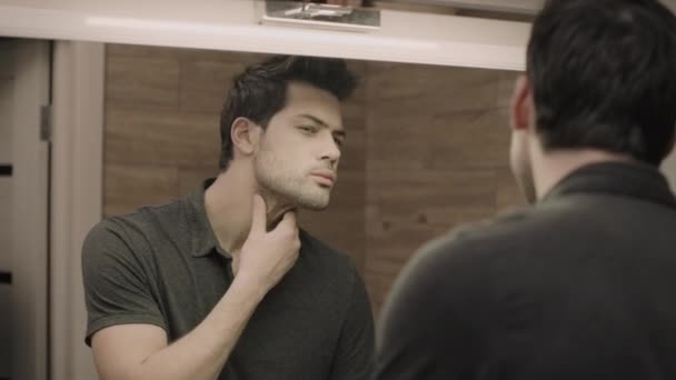 Jeune homme rasage visage en face du miroir à la salle de bain. Portrait de beau mec — Video