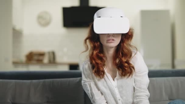 Femme sérieuse assise sur le canapé dans des lunettes vr. Femme choquée regardant vr . — Video