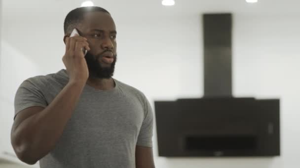 Angry black man talking phone at home. Young guy listening cellphone. — Stock Video