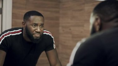 Arka adam aynanın önünde. Rahatsız Afrikalı adam banyoda depresif.