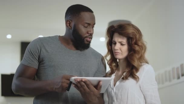 Genç çift birlikte evde mutfakta tartışıyor. Siyah adam resimleri gösteren — Stok video