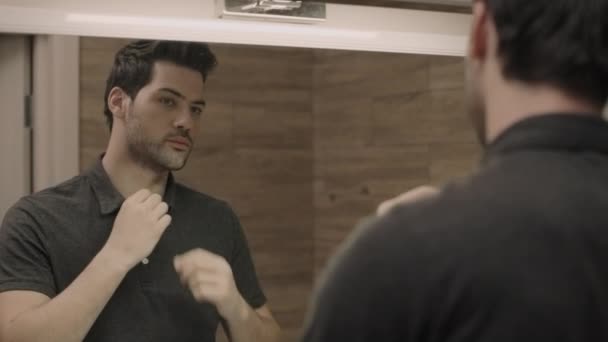 Un bel homme qui se regarde devant un miroir. Gros plan gars ajustement t-shirt — Video