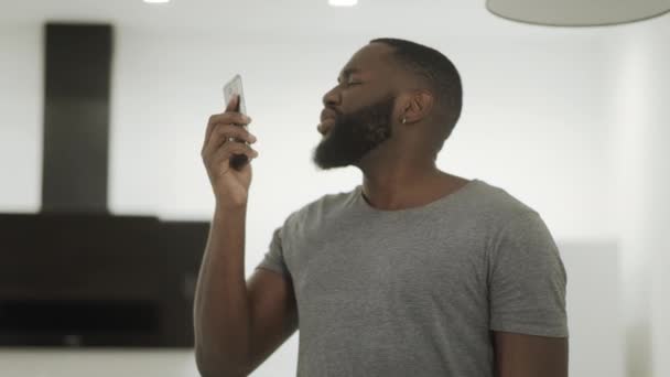 Upset black talking phone at home kitchen. Disappointed guy finishing phone talk — Stock Video