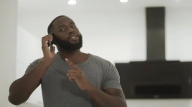 Siyah adam evde telefon konuşuyor tartışıyor. Telefon konuşan öfkeli adam.