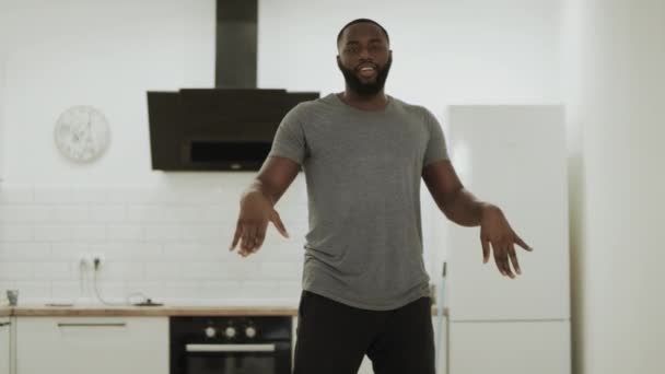 快乐的黑人男子跳舞机器人在开放式厨房。年轻人在家里移动缓慢. — 图库视频影像