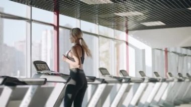 Spor salonunda koşu bandında koşan fitness kadını. Güzel kız kardiyo eğitimi olan.