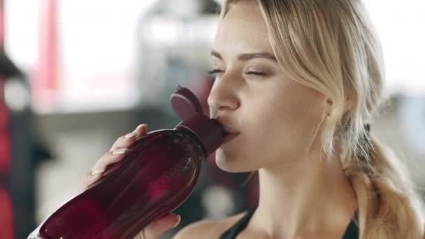 Smiling sport woman drinking water in fitness gym. Chica feliz bebiendo agua — Vídeo de stock