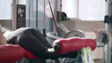 Spor salonunda spor simülatörü Fitness kadın eğitim bacak fleksiyon.