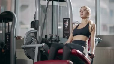 Spor kadın fitness salonunda fitness makinesi bacak egzersiz yapma.