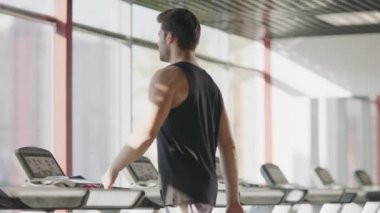 Fitness merkezinde koşu bandıüzerinde yürüyen atlet adam.
