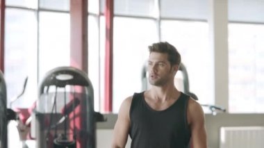 Yakışıklı adam fitness kulübünde dumbbells ile lunges egzersiz yapıyor.