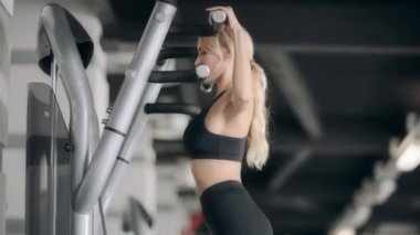 Spor kadın modern spor salonunda fitness makinesi üzerinde egzersiz kadar çekerek yapıyor.