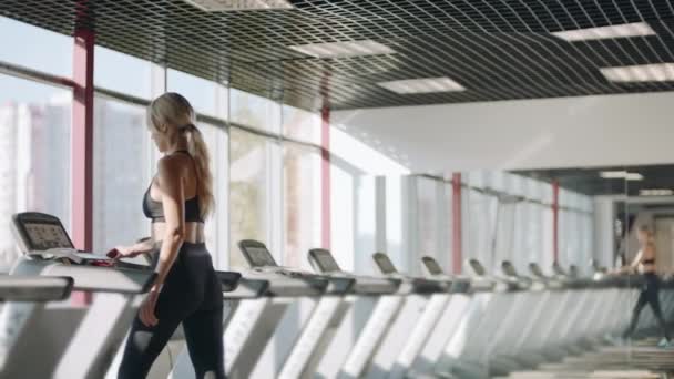 Jovem treinando em esteira rolante no clube de fitness. Mulher bonita formação cardio — Vídeo de Stock