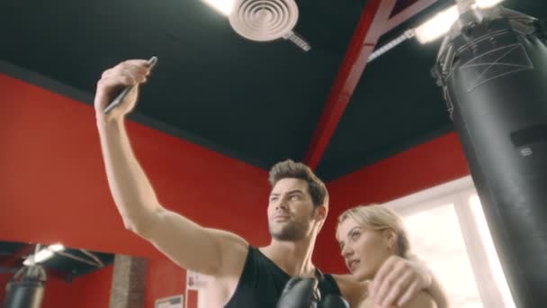 Alegre pareja abrazando para móvil selfie en gimnasio . — Vídeos de Stock