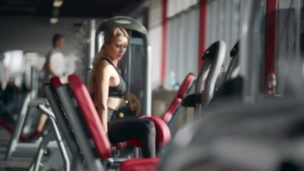 Güzel kadın spor kulübünde spor simülatörü fitness egzersiz yapıyor. — Stok video