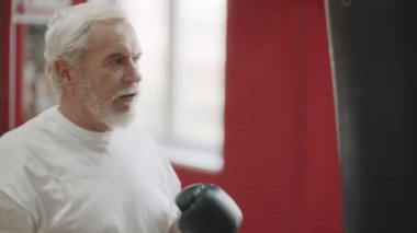 Gri saçlı adam dövüş kulübünde boks çantası na kick eğitim kick. Aktif üst düzey kavramı