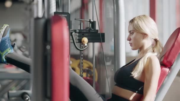 Spor kulübünde makinede Pretty fitness kız eğitim bacak basın. — Stok video